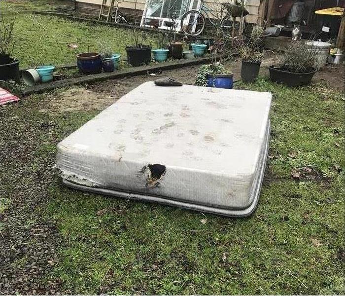 Mattress laying on the grass due to a fire damage from a charging cell phone
